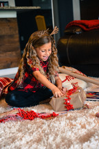 smiling little girl wrapping a Christmas present 