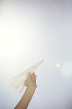 Raised hand holding a paper airplane.