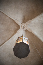 A lantern hanging from a church ceiling 