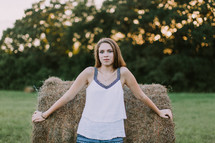teen girl standing in front of a hay bale 