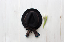 black hat and tulip on white wood boards 