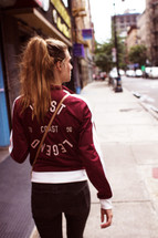 a young woman with a ponytail walking down a sidewalk 