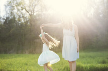 mother and daughter dancing outdoors in sunlight 