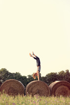 woman doing a handstand on hay bales 
