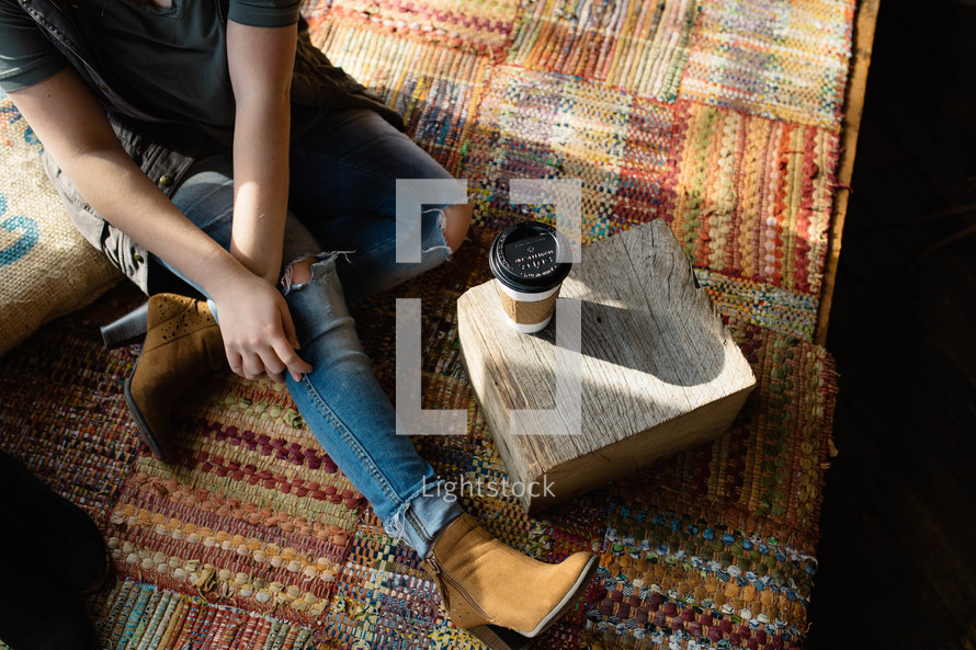 woman sitting on a rug and a cup of coffee 