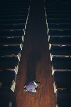 A man kneeling in the aisle of a church 