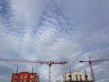 Buildings and industrial cranes against a cloudy sky.