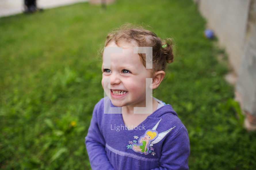 a smiling toddler girl standing in the grass 