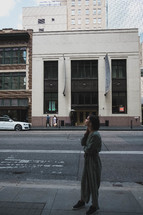 a woman standing on a downtown sidewalk looking up 