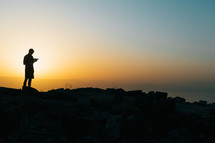 Silhouette of a man reading his Bible on a mountain at sunset in Hippos, Israel