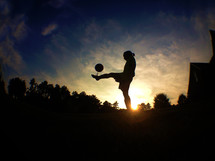 silhouette of a girl juggling a soccer ball 