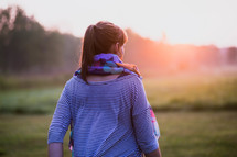 a woman in a scarf walking outdoors at sunrise 