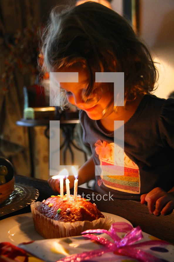 girl child blowing out a birthday cake 