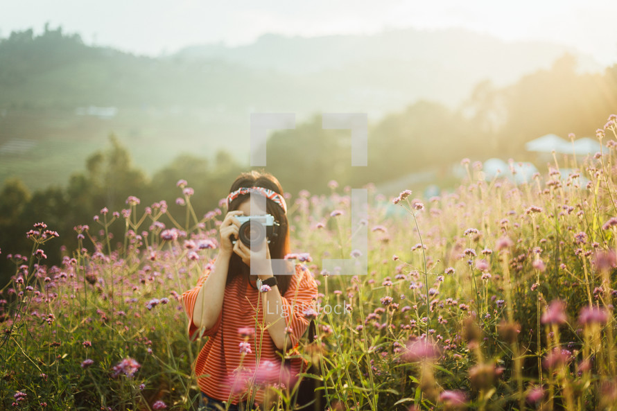 woman taking a picture in a field of flowers 
