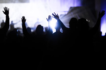 silhouettes of an audience with raised hands 