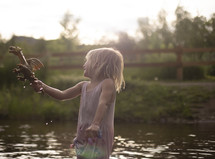 a girl playing with a toy dragon in a pond 