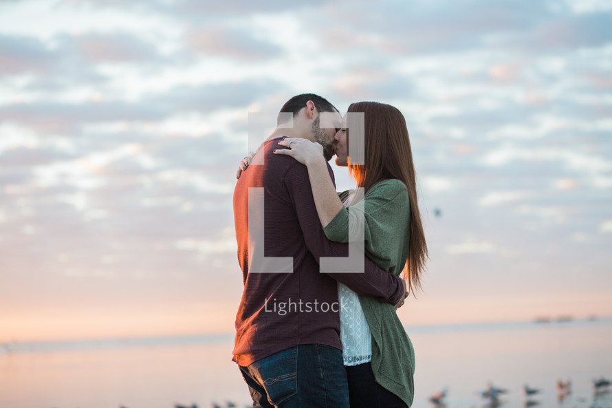 a couple hugging on a shore at sunset 