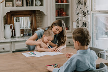 a mother coloring with her daughter and son 