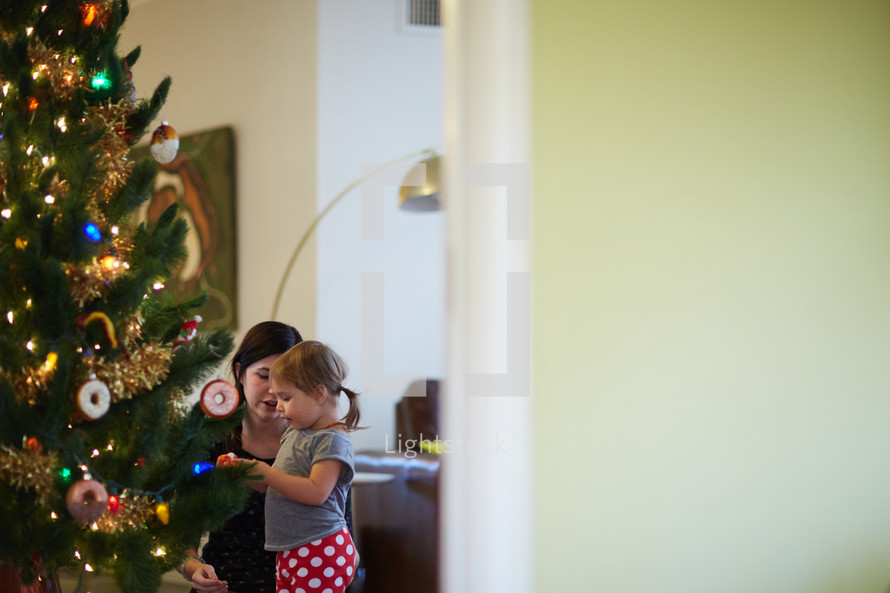 mother and daughter decorating a Christmas tree