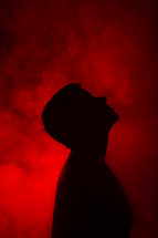 a man looking up to God standing in red glowing light 