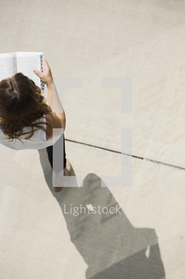 a woman walking while reading a Bible 