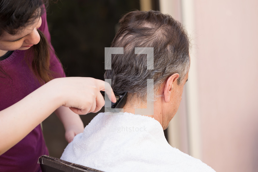 Family member cutting mans hair at home