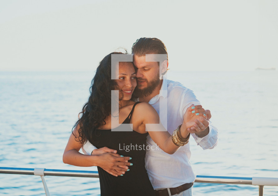 Energetic attractive young couple dancing latin Bachata near sea or ocean. Sunlight background. Summer time, romantic 
