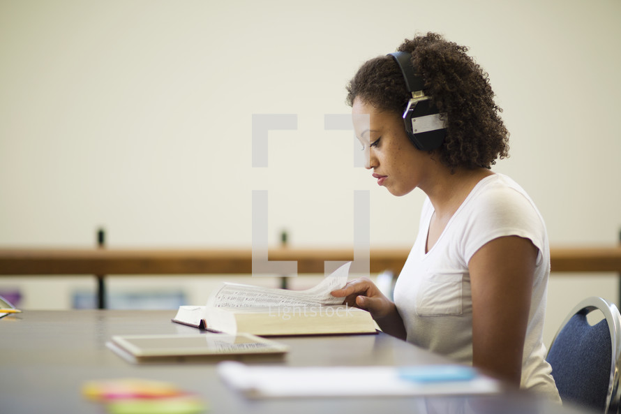 a woman reading a book and listening to headphones 