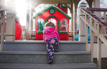 toddler girl climbing up steps to a Christmas display 