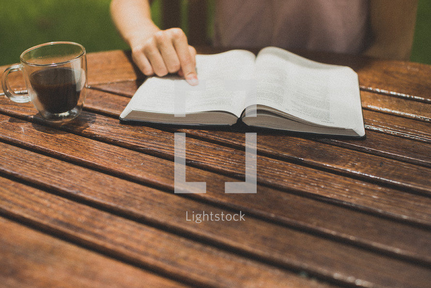 a young man reading a Bible in his backyard pointing to scripture 