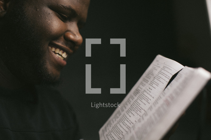 a man smiling reading a Bible 
