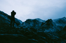 a man standing on a mountain taking pictures with a camera 