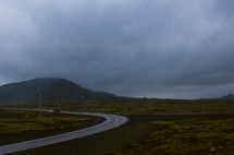 a curve on a mountain road under a cloudy sky