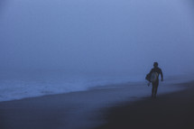 Surfer walking along the beach