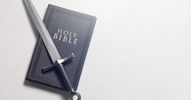 A Bible and Sword on a Bright White Background