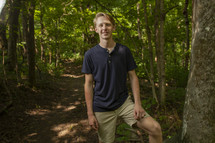 portrait of a teen boy standing in a forest 