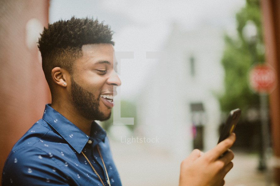 a man smiling looking at a cellphone screen 