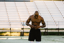 a shirtless man with tattoos standing on a football field 