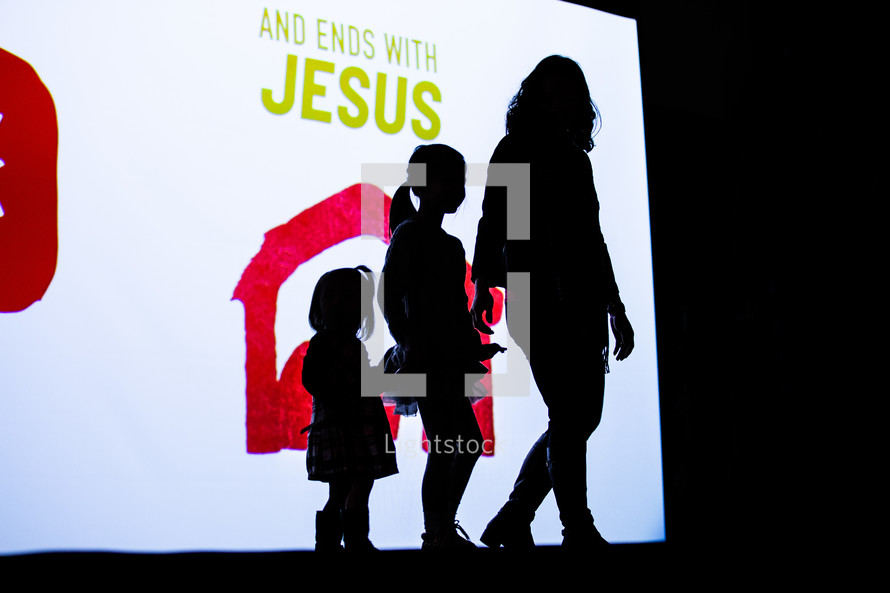 silhouette of a mother and her daughters during a church service 