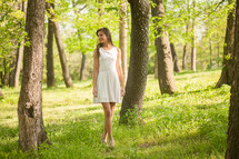 Woman walking through the trees and grass.
