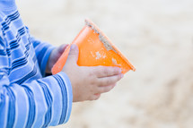 a child's hands holding a sand bucket 