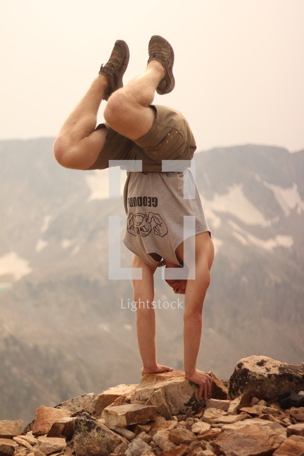 a man doing a handstand on a mountain top 