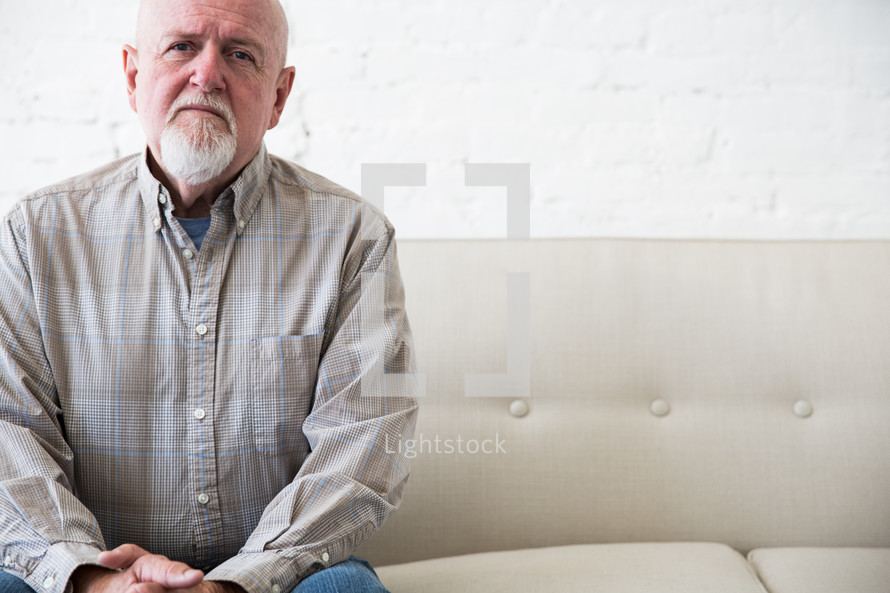 an elderly man sitting on a couch alone 