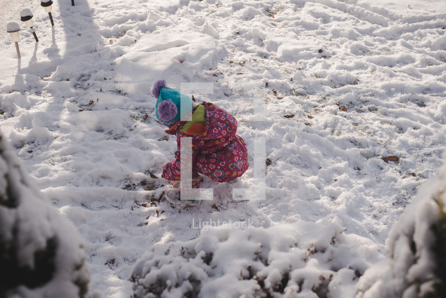 toddler girl playing in snow 
