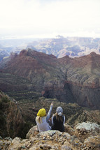 women sitting on the side of a mountain looking out at canyons