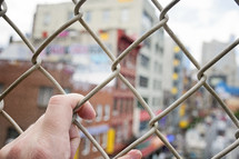 hands grasping a chain link fence 