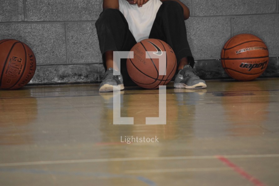 An African American boy waiting on the sidelines to join a basketball game 