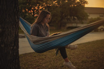 a teen girl in a hammock reading a Bible 
