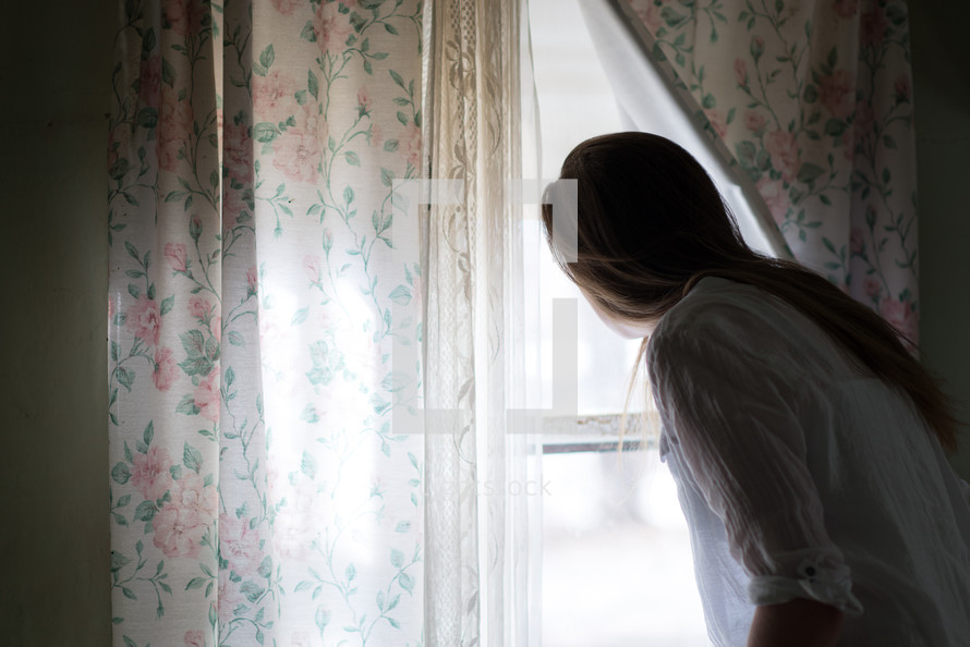 young woman looking out a window 