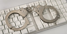 Handcuffs lying on a computer keyboard.